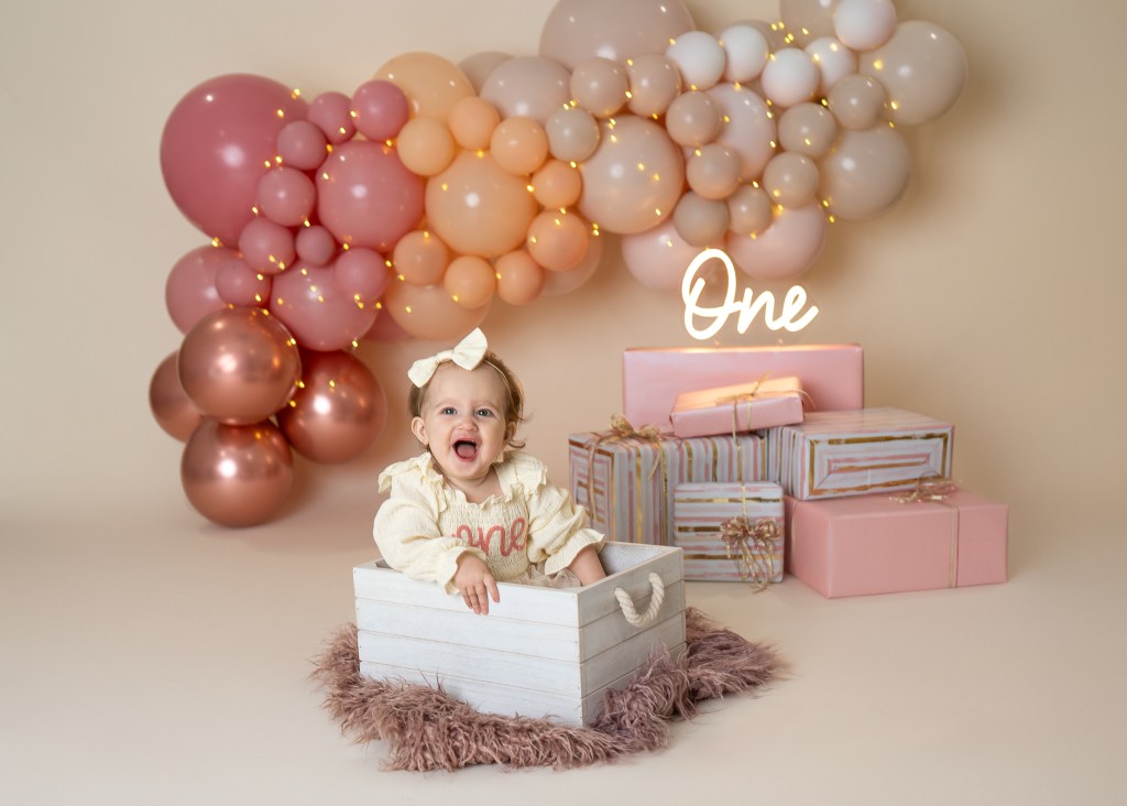 cheerful baby posed in a crate at her custom designed Sarasota upscale cake smash
