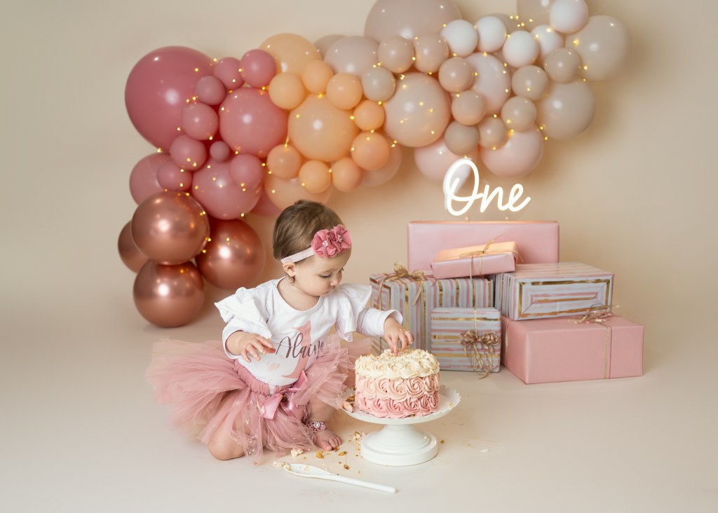 Baby girl curiously investigates her cake during her first birthday cake smash in Sarasota