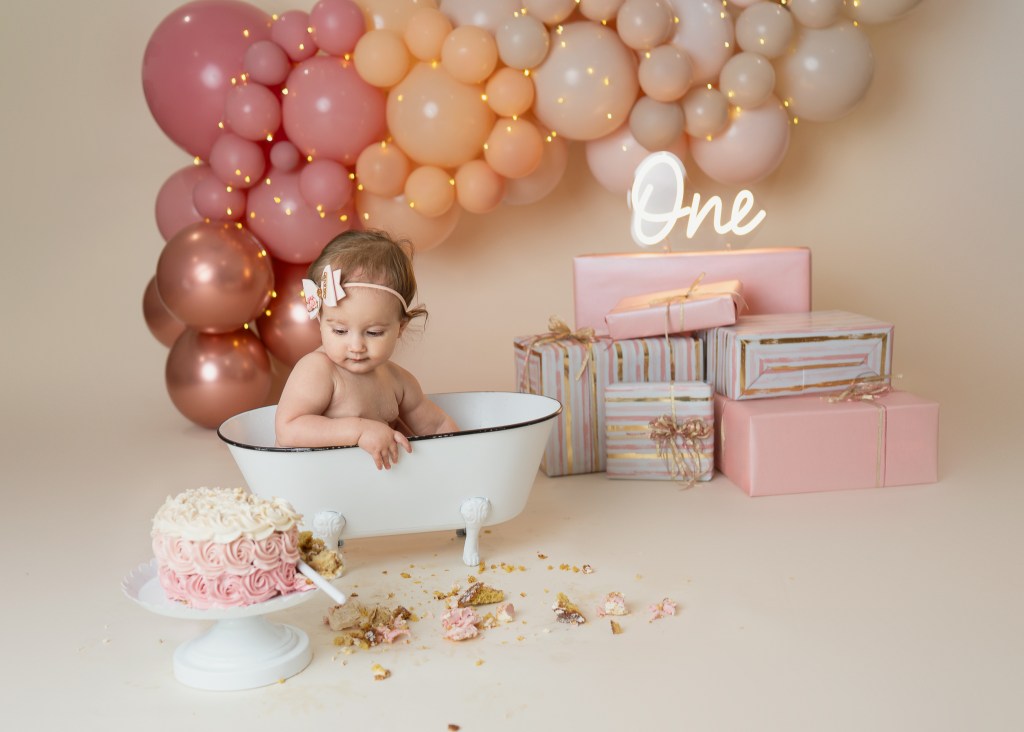 baby eyeing her cake from the splash tub of her sarasota cake smash and splash session