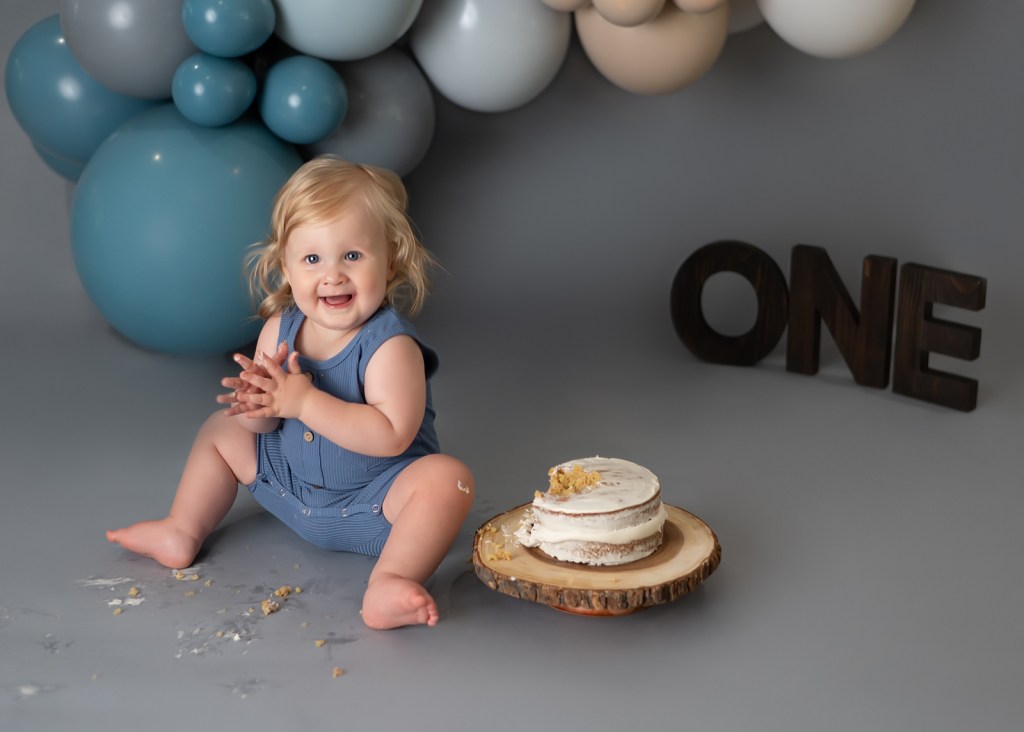 Baby boy on his first birthday with his cake and balloons