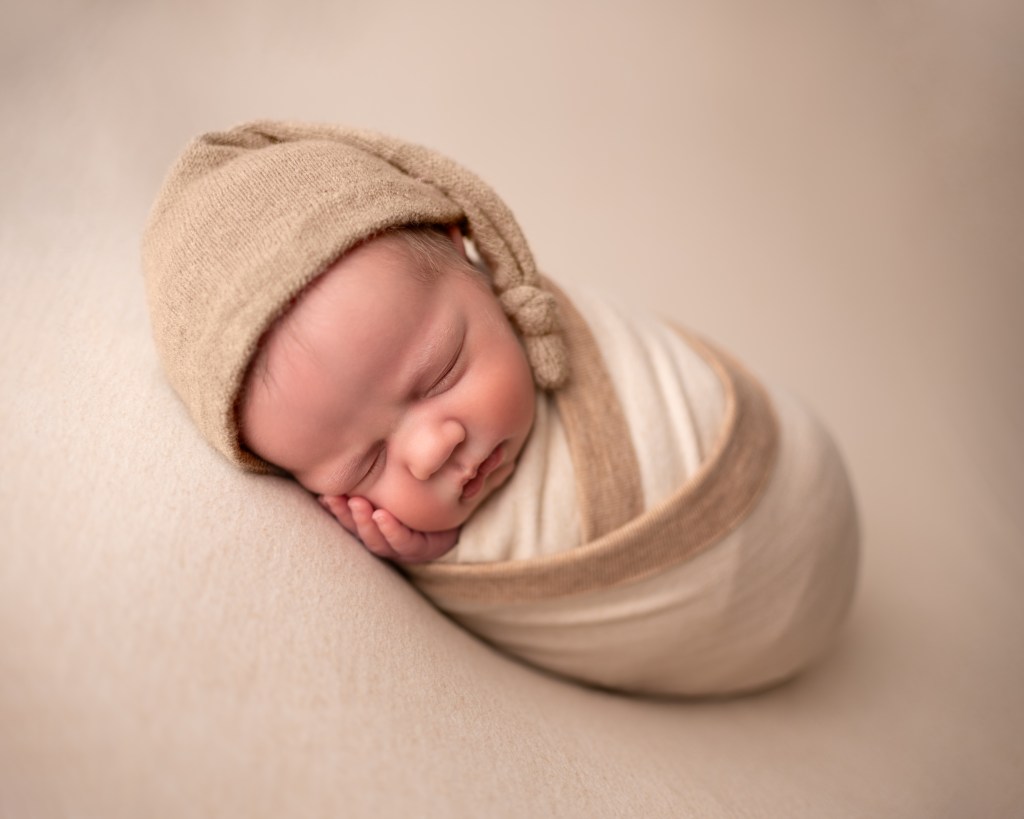 Peaceful, soothed newborn swaddled in a tan set during photo session –Soothe Your Newborn