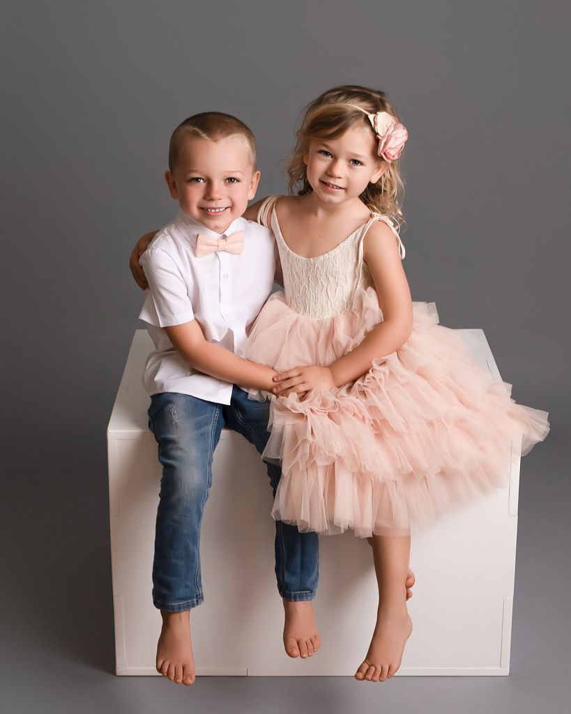 Brother and sister posed together during a studio portrait session.