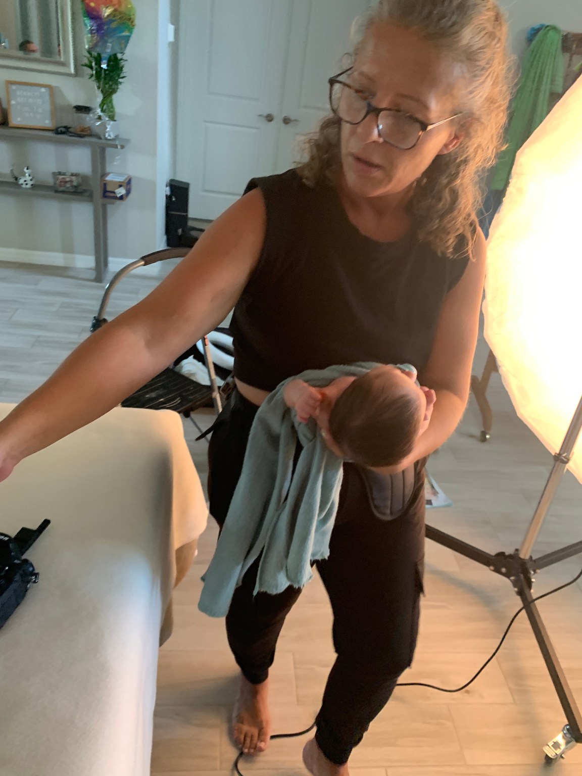 newborn photographer holding baby preparing for the next pose